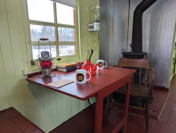Train features, a wooden breakfast table beside a window, with a wood stove in the background