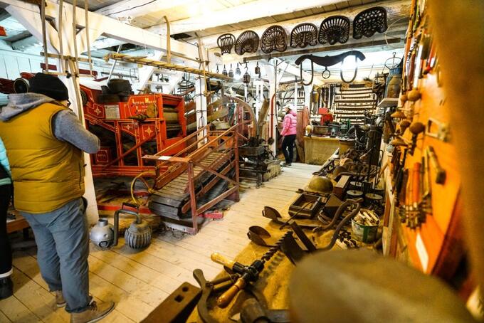 two people perusing large display of antique maple harvesting tools at Wheeler Pancake House