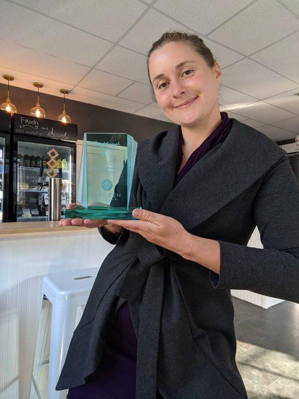 Women smiling holding a business award in her cafe